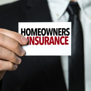 Man holding a business card that reads "homeowners insurance" - Your Injury Law Group